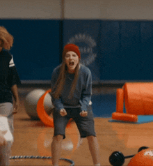 a woman wearing a red hat is standing in a gym