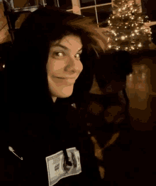 a young man with red hair is wearing a black hoodie with a dollar bill on it and a christmas tree in the background .