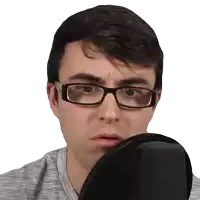 a man wearing glasses and a gray shirt looks at himself in a mirror