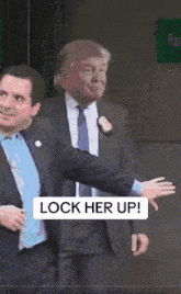 two women in suits and ties are standing next to each other with a sign that says " lock her up "