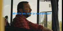 a man in a red plaid shirt is looking out a window with the words " eli mile bre ko ti je oval serenja "