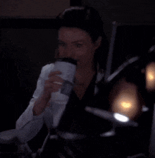 a woman in a lab coat is sitting in a dark room looking at something .