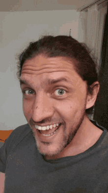 a man with long hair and a beard is smiling and making a funny face