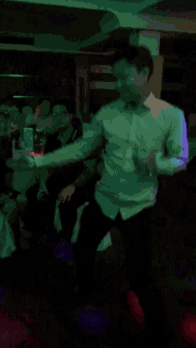 a man in a white shirt is dancing in the dark