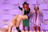 a woman in a green skirt is kicking another woman in a white dress