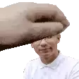 a man in a white shirt is being slapped on the head by a hand .