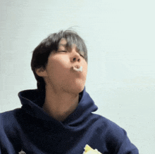 a man wearing a blue hoodie is eating a banana