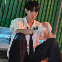 a man in a white shirt and black tie is sitting on the floor