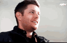 a man is smiling in front of a tv screen that says axn on it