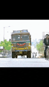 a man riding a bike down a street in front of a truck that has a license plate that starts with the letter s
