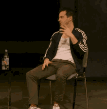 a man is sitting in a chair with a bottle of water in the background