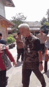 a man with a name tag on his chest is walking in a crowd of people .