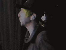 a man wearing a black hat is standing in the dark