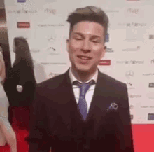 a man in a suit and tie is smiling on a red carpet