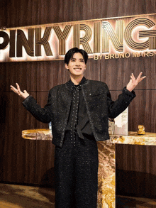 a man stands in front of a pinky ring by bruno mars sign