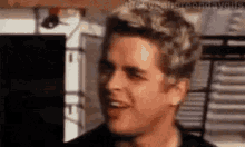 a close up of a man 's face with blonde hair making a funny face in a room .