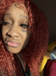 a woman with red hair has a tattoo on her forehead