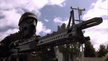 a soldier wearing a gas mask holds a machine gun