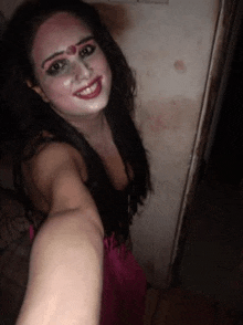 a woman is taking a selfie in a dark room with her face painted .