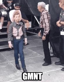 a young boy in a cowboy outfit is standing next to an older man with the word gmnt on the floor