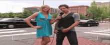 a woman in a blue dress is interviewing a man with a microphone
