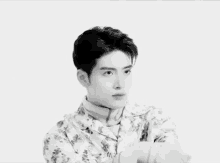 a black and white photo of a young man wearing a floral shirt and tie .