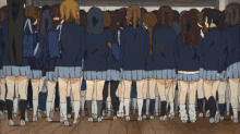a large group of girls in school uniforms are standing in a classroom