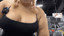 a woman in a black tank top stands in a gym