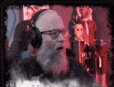 a man with a beard and glasses is wearing headphones and sitting in a chair .