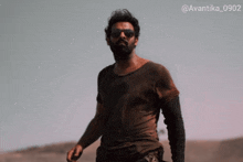 a man wearing sunglasses and a brown shirt with the hashtag avantika_0902 on the bottom right