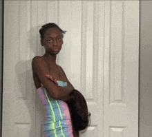 a woman in a tie dye dress is standing in front of a white door .
