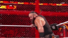 a man in a black tank top is standing in a wrestling ring holding a sword .