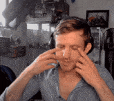 a man wearing headphones and a striped shirt looks at his face