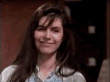 a woman with long hair is smiling for the camera .