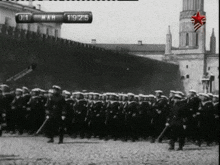 a black and white photo of a military parade with a clock that says 1911 on it