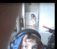 a boy wearing headphones looks at the camera while a girl stands in the background