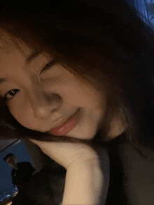 a woman with her hand on her face looks at the camera