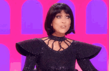 a woman wearing a black dress and a wig is making a face