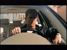 a man is driving a car with a black jacket on