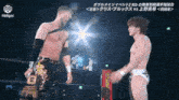 two wrestlers are shaking hands in a ring with chinese writing on the screen