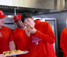 a man wearing a red hoodie that says angels eating a hamburger