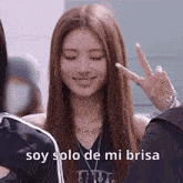 a woman with long hair is making a peace sign with her eyes closed