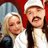 a man with long hair and a mustache wears a white hat that says ' athletic club ' on it