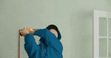 a man wearing a blue hoodie is holding a yellow object