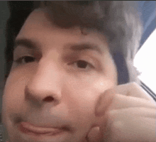 a close up of a man 's face with a hand on his face .