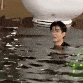 a man is swimming in a pool with a white balloon in the background .