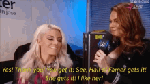 a woman is talking into a microphone while another woman looks on and says " yes "