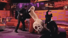 a man in a suit is standing next to a stuffed dog