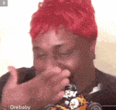 a man with red hair is covering his mouth while holding a toy .