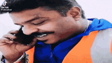 a man is talking on a cell phone and smiling .